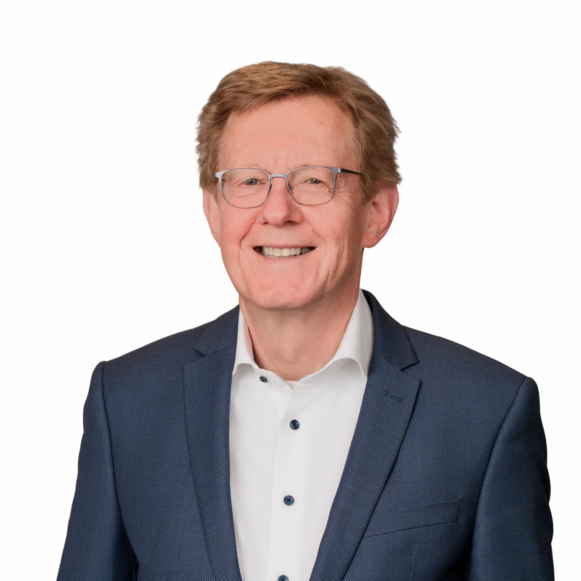 Een professioneel portret van een vriendelijk glimlachende man met een bril en kort, bruin-blond haar, gekleed in een wit overhemd en een donkerblauw colbert tegen een witte achtergrond.